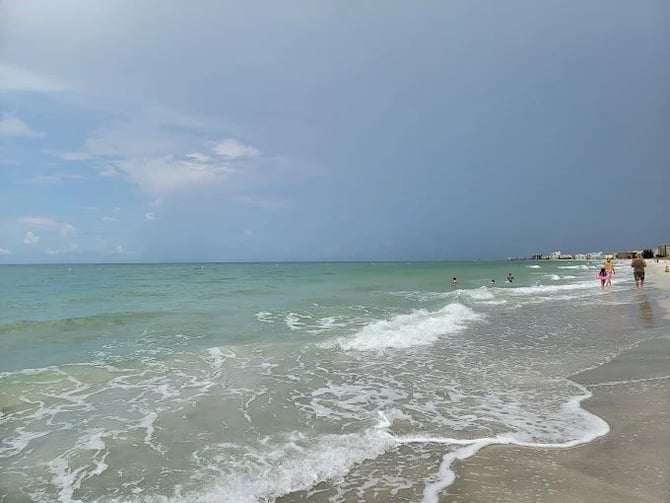 Gulf shoreline with turquoise water and people walking the beach